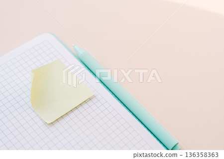 Sticky note and mint pen on grid notebook, minimal stationery flat lay Sticky note and mint pen on grid notebook, minimal stationery flat lay 136358363