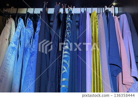 Textured fabrics and clothing items in a wardrobe 136358444