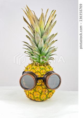 Funny pineapple wearing vintage steampunk goggles on light background, quirky tropical concept, minimal studio style 136358769