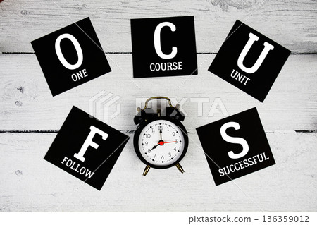 FOCUS Follow One Course Unit Successful with alarm clock on wooden background FOCUS Follow One Course Unit Successful with alarm clock on wooden background 136359012