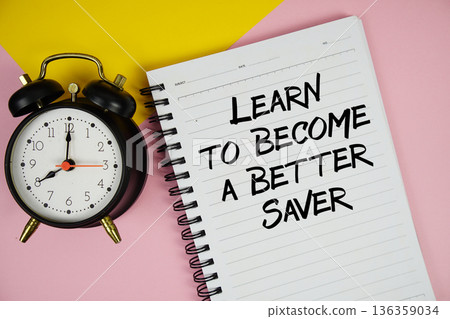 Learn to Become a Better Saver text written on notepad with alarm clock on pink background Learn to Become a Better Saver text written on notepad with alarm clock on pink background 136359034