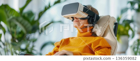 Senior woman in a wheelchair using virtual reality headset. 136359082