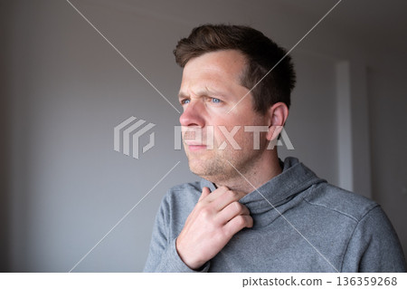 Pensive young man standing at home thinking about problems and making decisions Pensive young man standing at home thinking about problems and making decisions 136359268