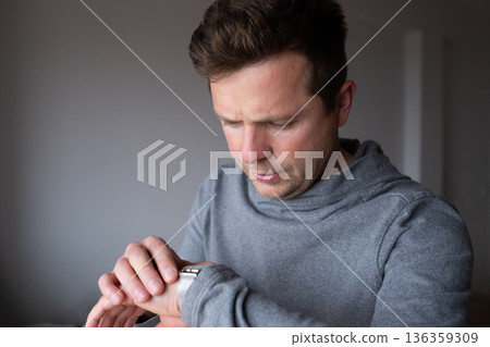 Surprised man looking at his wristwatch realizing the clock has stopped working 136359309