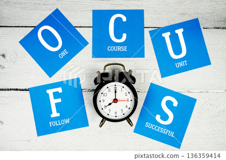 FOCUS Follow One Course Unit Successful with alarm clock on wooden background FOCUS Follow One Course Unit Successful with alarm clock on wooden background 136359414
