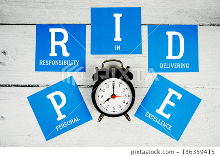PRIDE Personal Responsibility In Delivering Excellence with alarm clock on wooden background 136359415