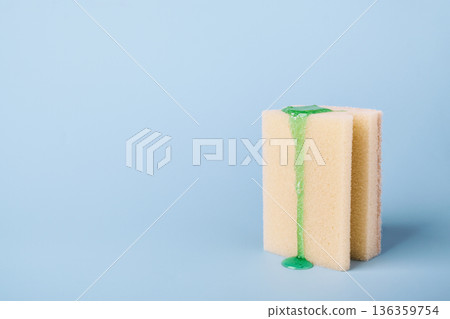 Cleaning sponge with liquid dishwashing detergent dripping on light blue background Cleaning sponge with liquid dishwashing detergent dripping on light blue background 136359754
