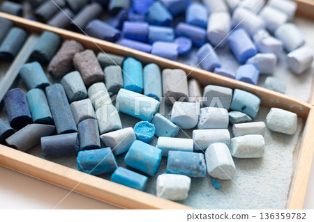 Set of soft pastel crayons in pink, red, and yellow in a wooden artist's box. Broken crayons, top view Set of soft pastel crayons in pink, red, and yellow in a wooden artist's box. Broken crayons, top view 136359782