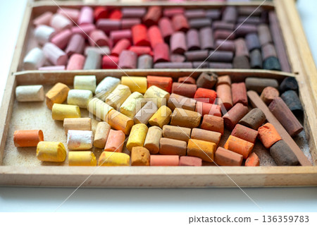 Set of soft pastel crayons in pink, red, and yellow in a wooden artist's box. Broken crayons, top view Set of soft pastel crayons in pink, red, and yellow in a wooden artist's box. Broken crayons, top view 136359783