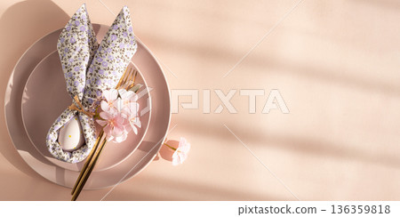 Easter Table Setting with Bunny Napkin and Decorated Egg. Festive Spring Arrangement on Pink Background Easter Table Setting with Bunny Napkin and Decorated Egg. Festive Spring Arrangement on Pink Background 136359818