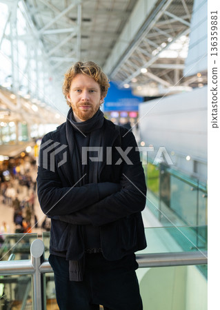 Young man standing in modern airport terminal building Young man standing in modern airport terminal building 136359881