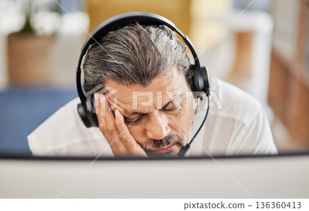 Exhausted, customer service and male consultant sleeping in his office doing an online consultation. Fatigue, burnout and tired mature man telemarketing agent taking a nap with a headset in workplace 136360413