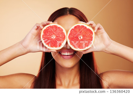 Beauty, grapefruit and a woman with skin care in studio for natural dermatology, cosmetics or wellness. Facial, fruit and healthy diet for detox or nutrition of model person on a brown background 136360420