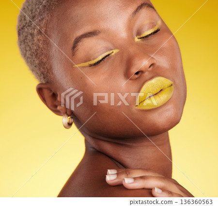 Cosmetic, art and woman in a studio with makeup eyeliner and lipstick for cosmetology. Beauty, creative and young African female model with a colorful glamour face routine by a yellow background. Cosmetic, art and woman in a studio with makeup eyeliner and lipstick for cosmetology. Beauty, creative and young African female model with a colorful glamour face routine by a yellow background. 136360563