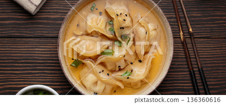 Gyoza dumplings broth soup chopsticks wooden background bowl asian wontons 136360616
