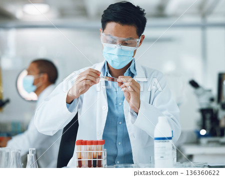 Exam, blood sample and scientist doing research with face mask in a laboratory for medical analysis in a lab. Science, medicine and professional Asian man working on test of DNA in a vial tube 136360622