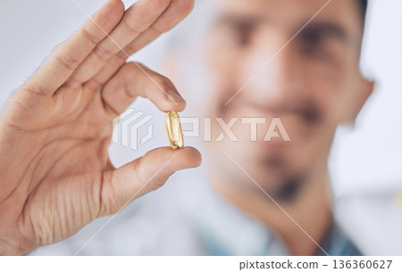 Man, hand of doctor and pill, pharmaceutical drugs and treatment of illness at hospital with blurred background. Healthcare, medicine and medical professional with gold capsule to help with health. 136360627