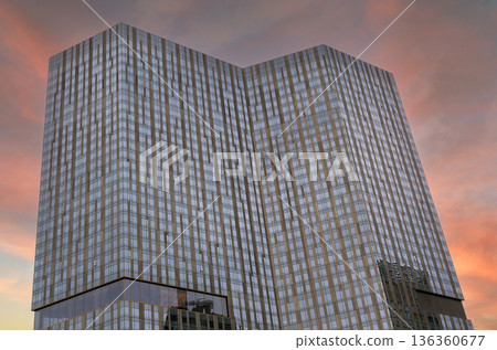 Sunset view of modern glass building in an urban area reflective windows architectural details 136360677