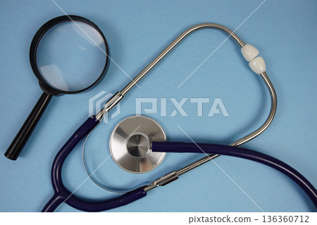 Stethoscope and magnifying glass with space copy for text on blue background 136360712