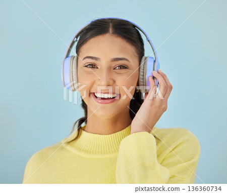 Portrait of happy woman, headphones and mockup in studio listening to podcast, mobile app and streaming radio site. Smile, music media subscription and sound, face of girl on blue background space. Portrait of happy woman, headphones and mockup in studio listening to podcast, mobile app and streaming radio site. Smile, music media subscription and sound, face of girl on blue background space. 136360734