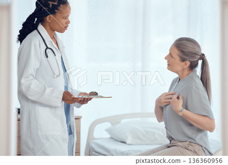 Healthcare, consultation and doctor with senior patient in discussion on chest pain problem. Professional, clipboard and female medical worker talking to elderly woman with heart sickness in hospital 136360956