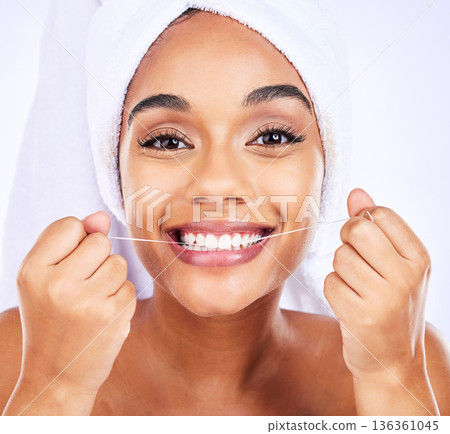 Dental floss, teeth and face of a woman for health and wellness in studio. Portrait of a young female model flossing, cleaning and self care for fresh breath, hygiene and shine on a white background 136361045