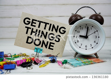 Getting Things Done text on paper card with alarm clock and stationary on wooden background 136361180
