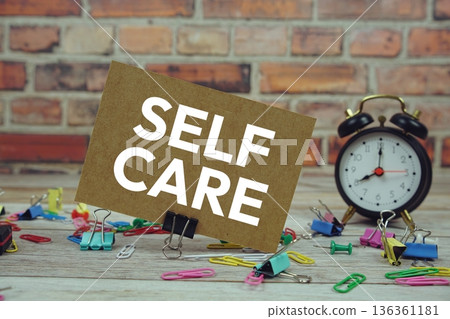 Self Care text on paper card with alarm clock and stationary on wooden background 136361181