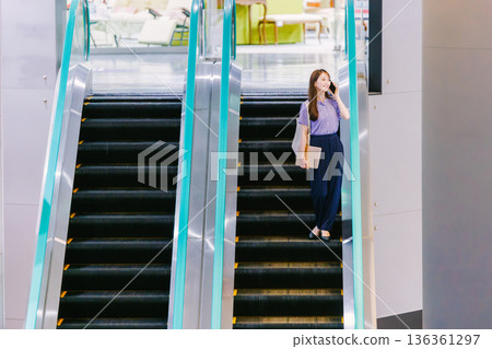 A woman on the escalator making a phone call 136361297