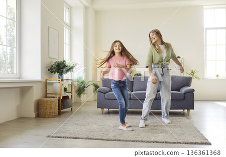 Joyful mother and daughter dancing together in bright spacious living room Joyful mother and daughter dancing together in bright spacious living room 136361368