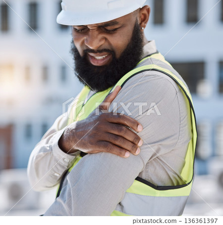 Injury, arm pain and a black man construction worker on a building site, feeling fatigue in his shoulder. Burnout, emergency or accident and a male engineer holding his muscle with inflammation 136361397