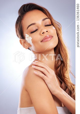 Skincare, woman with flower and cream on face, natural makeup and spa treatment on white background. Dermatology, beauty and glow, model with floral lotion and organic facial cosmetics in studio. Skincare, woman with flower and cream on face, natural makeup and spa treatment on white background. Dermatology, beauty and glow, model with floral lotion and organic facial cosmetics in studio. 136361460