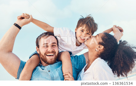 Beach, father and a mother kiss child on the cheek while on a vacation, holiday or adventure. A woman, man and kid on shoulders for a portrait outdoor of summer fun and travel with multiracial family Beach, father and a mother kiss child on the cheek while on a vacation, holiday or adventure. A woman, man and kid on shoulders for a portrait outdoor of summer fun and travel with multiracial family 136361534