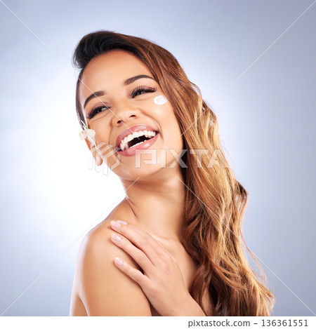 Beauty, flower and happy woman with cream on face, natural makeup and treatment on white background. Dermatology, skincare and smile, model with floral lotion and organic facial cosmetics in studio. 136361551