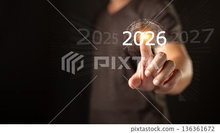 A person touches a glowing digital interface highlighting the year 2026 between 2025 and 2027, symbolizing future planning, technology, progress, and strategic vision for upcoming opportunities. 136361672