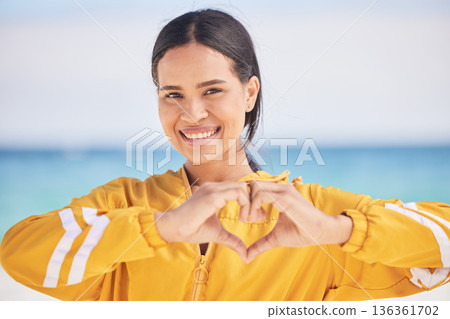 Happy woman, portrait and heart hands on beach for love, care or support in trust, health or romance. Outdoor female person with emoji, symbol or icon for like or wellness in peace, sign or emoticon 136361702