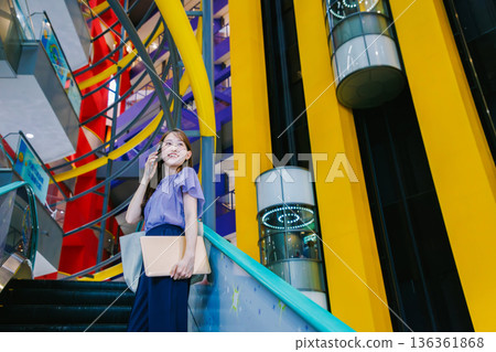 A woman on the escalator making a phone call 136361868