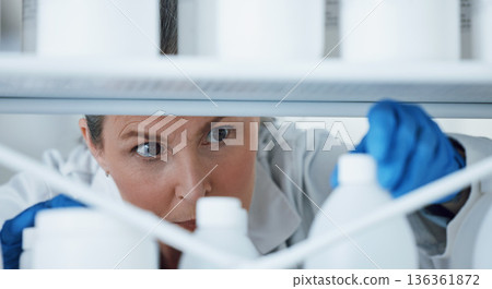 Laboratory, research and woman with bottles on a shelf, check information, medical and science. Healthcare, medicine and researcher with innovation in manufacturing of vaccine, chemical and inventory 136361872