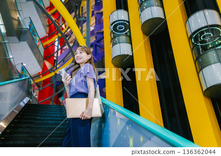 A woman on the escalator making a phone call 136362044