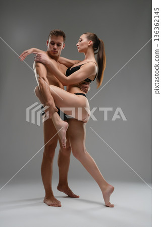 Athletic couple in a passionate contemporary dance pose against a gray background. 136362145