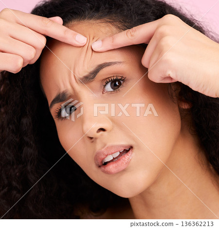 Skincare, woman and worried or squeeze pimple for dermatology in pink studio background. Frustrated, face and girl with acne or skin problem with facial treatment for self care, anxiety or stress. Skincare, woman and worried or squeeze pimple for dermatology in pink studio background. Frustrated, face and girl with acne or skin problem with facial treatment for self care, anxiety or stress. 136362213