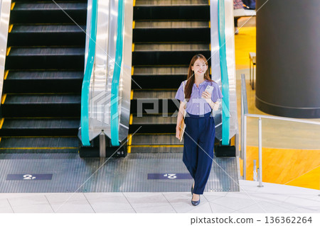 A woman on the escalator making a phone call 136362264