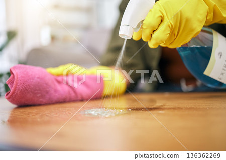 Person, hands and spray on table with cloth for hygiene, bacteria or germ removal at home. Closeup of cleaner, housekeeper or maid wiping furniture in domestic service or disinfection on desk surface Person, hands and spray on table with cloth for hygiene, bacteria or germ removal at home. Closeup of cleaner, housekeeper or maid wiping furniture in domestic service or disinfection on desk surface 136362269
