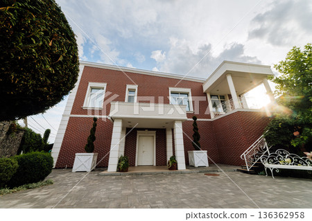 Front entrance of modern brick house with white columns, porch and closed door 136362958