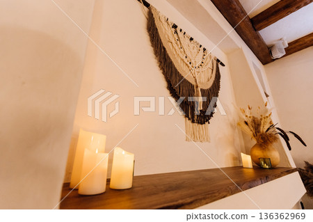 Boho macrame wall hanging with candles and dried flowers on rustic shelf Boho macrame wall hanging with candles and dried flowers on rustic shelf 136362969