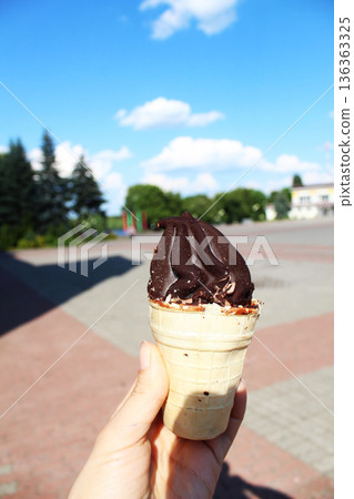 Ice cream in hand in summer in the park. Chocolate ice cream Ice cream in hand in summer in the park. Chocolate ice cream 136363325