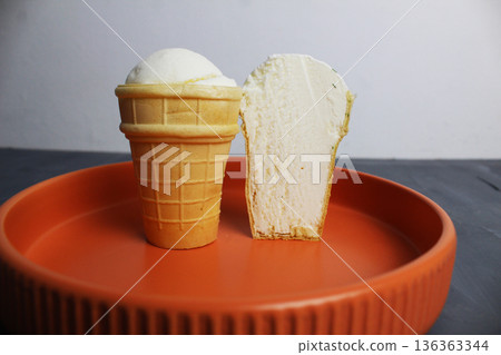 Frozen Creamy in Waffle Cup Cut on Orange Plate on Gray Background 136363344