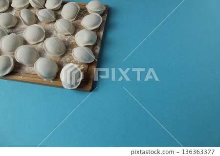 Frozen dumplings on a board on a blue background with space for copyspace text. Semi-finished products for vegetarians 136363377