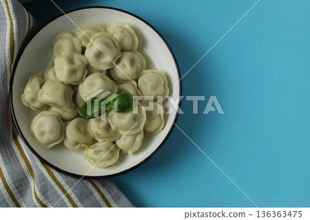 dumplings in a plate on a blue background with space for copyspace text top angle top view from above. Studio shooting of food, homemade dishes dumplings in a plate on a blue background with space for copyspace text top angle top view from above. Studio shooting of food, homemade dishes 136363475