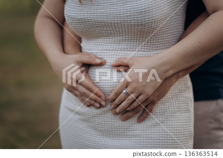 Close up of expecting couple hands on pregnant belly, maternity love and family Close up of expecting couple hands on pregnant belly, maternity love and family 136363514